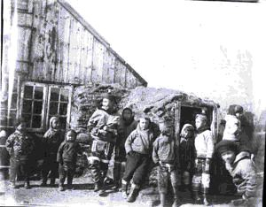 Image of Woman and 10 children by frame/sod house