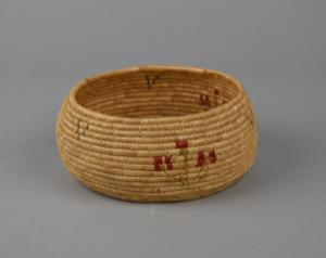 Image: Coiled grass basket with red and green plants on sides and 3 small blue designs