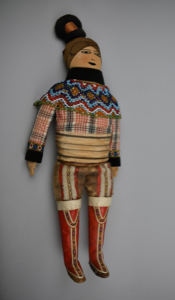 Image: Doll dressed in Sunday best from South Greenland with decorated red boots and beaded collar and cuffs