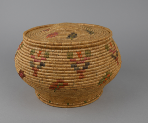 Image: bowl-shaped coiled woven basket with geometric designs and a cover