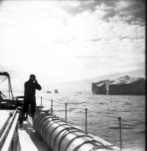 Image of Captain  at the rail, taking picture, of iceberg. Melville Bay