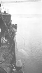 Image of Eskimo [Inuk] on ship throwing harpoon at ?