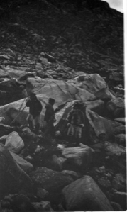 Image of 3 Eskimos [Inuit] among rocks