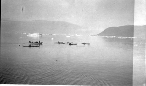 Image of Eskimos [Inuit] in an open boat, and 7 kayakers