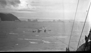Image of Teams on ice near ship; icebergs beyond