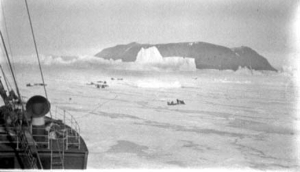Image of Teams scattered on ice near ship; icebergs beyond