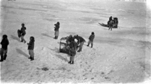 Image of Eskimos [Inuit] carrying items from a sledge