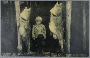 Image of Small boy in period dress with large hanging fish;(message from Mrs. G.K. Sabin)