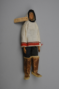 Image of Eastern Inuit wooden man doll in white cloth parka, red & black trim, denim