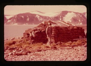 Image of Eskimo [Inughuit] sod hut. Sgt. D. Craven, U.S.A.F. standing by