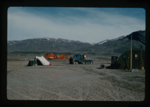 Image of View of logistics vehicles at base camp, 2 U.S. Army helicopters, large tracked