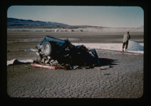 Image of Destroyed jeep in foreground. Jack Crowell prepares markings on runway