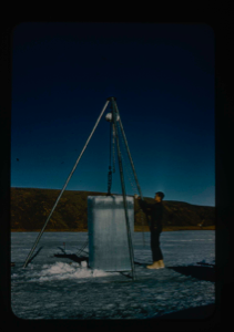 Image of Cabaniss removing block of ice cut from Lake for strength tests 