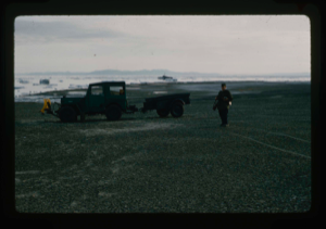 Image: Jeep and trailer on shore of Polaris Bay after landing by barge from USS Atka. 