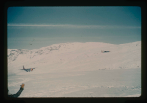 Image of C-54 aircraft flies cover as C-130 land on skis on Centrum Lake. Snow 4-6 feet