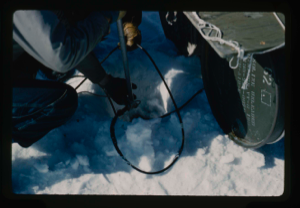 Image of Installing thermistor cable into drill hole through snow and ice of Centrum Lake