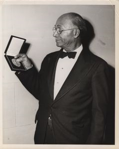 Image of Matthew Henson Admires his Chicago Geographic Society Gold Medal