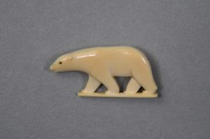 Image of Polar bear. Black eye, carved mouth. Bear is standing on small piece (clasp carv