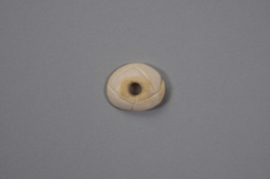 Image: Ivory disc with drilled hole through center and carved line on one side
