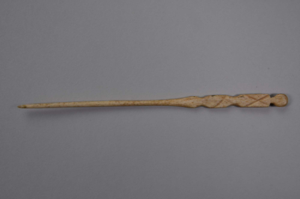 Image: Crochet hook with wide end connected to two rectangular figures with Xs through