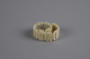 Image: Bracelet. Curved square segments with figure & animal cut-outs glued to each 