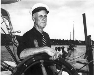 Image of Donald MacMillan at wheel after sailing day ceremonies