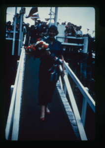 Image: Departure Day. Miriam MacMillan with bouquet, walking down gang plank. Donald Ma