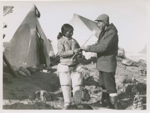 Image of Eskimo [Inuk] woman giving Miriam MacMillan a louse catcher