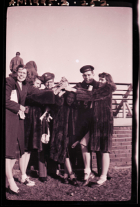 Image of Four young women and two Navy men holding bottle (?)