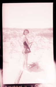 Image of Young woman in bathing suit gathering branches