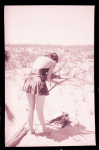 Image of Young woman in bathing suit gathering branches