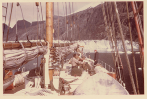 Image of Schooner Bowdoin near glacier face. Miriam and crew on deck