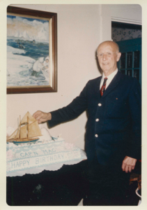 Image of Donald MacMillan standing by his 90th birthday cake