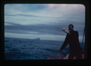 Image of Ian White throwing bottle with a record overboard. (2 copies)