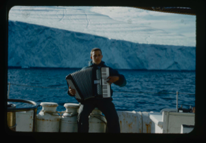 Image of Tiger playing his accordion, aboard. (2 copies)