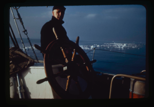 Image of Donald MacMillan at wheel. Ice pack beyond (2 copies)