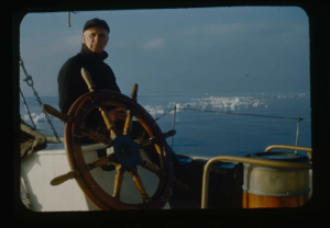 Image of Donald MacMillan at wheel. Ice pack beyond.