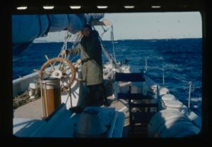 Image of Miriam MacMillan at wheel. Iceberg beyond.