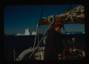 Image of Miriam MacMillan at wheel. Iceberg beyond