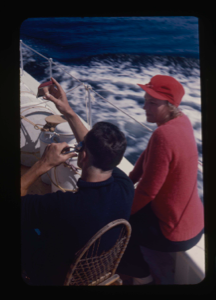 Image of Miriam MacMillan watching crewman trimming his hair on deck