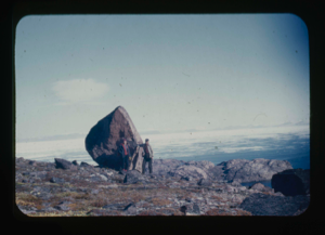 Image of ? and Miriam MacMillan standing by huge boulder. Ice field beyond