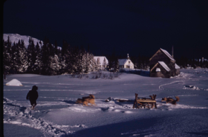 Image of Child and dogs playing in snow near church.