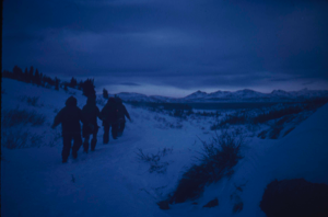 Image: Inuit walking through snow at twilight.
