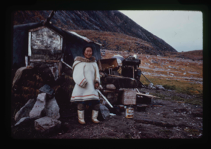 Image of Eskimo [Inuk] woman in front of her home