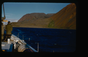 Image of Donald MacMillan by rail looking at mountains at Etah