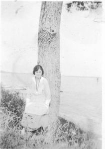 Image of Young woman leaning against tree
