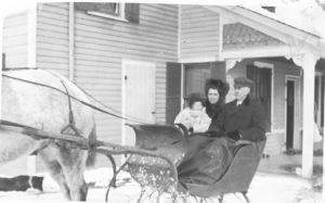 Image: Young woman, child, and older man (Grandpa Wood?) in sleigh. 