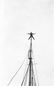 Image: Donald MacMillan spread-eagle on mast peak