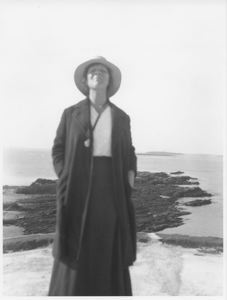 Image of Woman in hat and open coat standing on bluff (or library roof?)