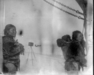 Image of 2 Inuit women aboard, one with baby in hood. Camera on tripod beyond